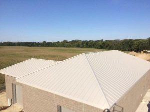 aerial view of sheet metal roof on a brick building with fields and trees in background