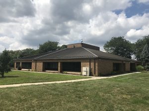 Small building at top of hill with large windows and clean sheet metal roof